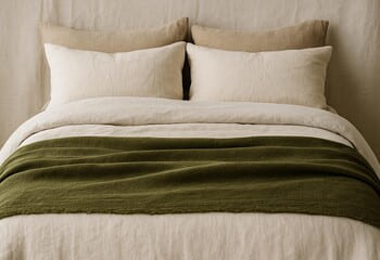 Zeytin yeşili şal ile katmanlanmış yatak: keten dokunun doğal nefesi